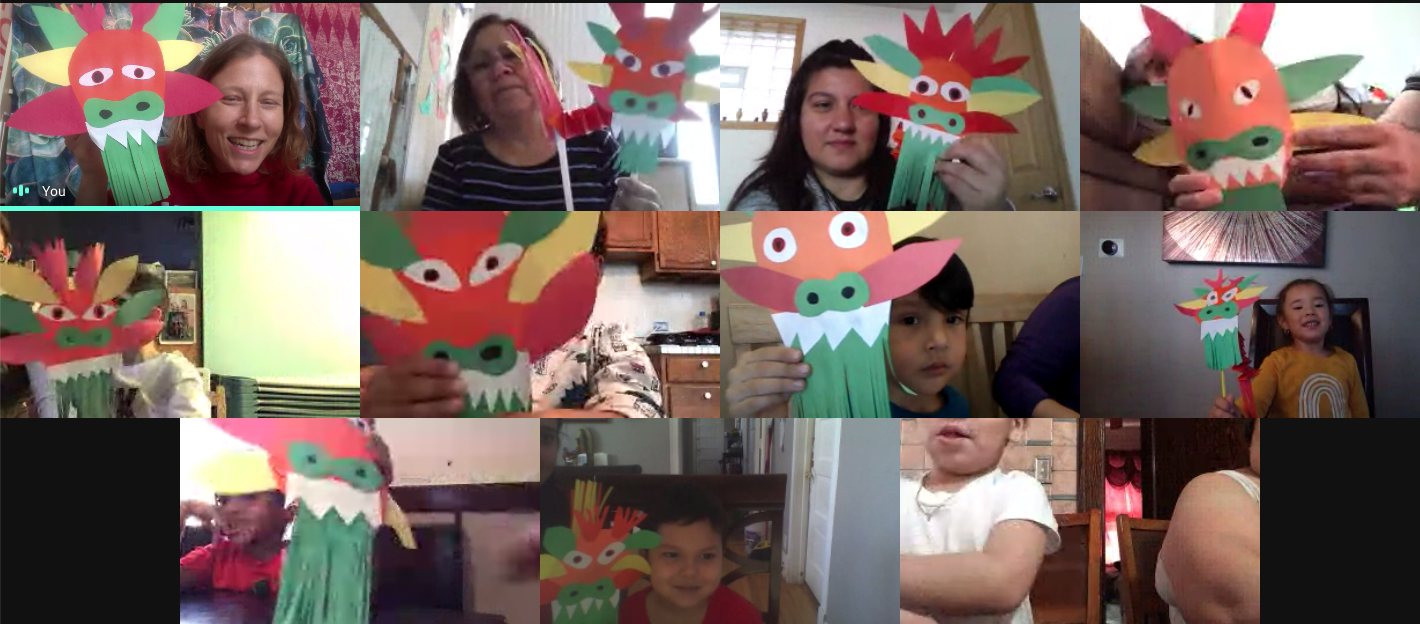 A virtual inclusion pre-K program is in session with 11 people, each holding up a dragon made of red, green, yellow and orange construction paper. Some children are smiling, others hide behind their dragons.